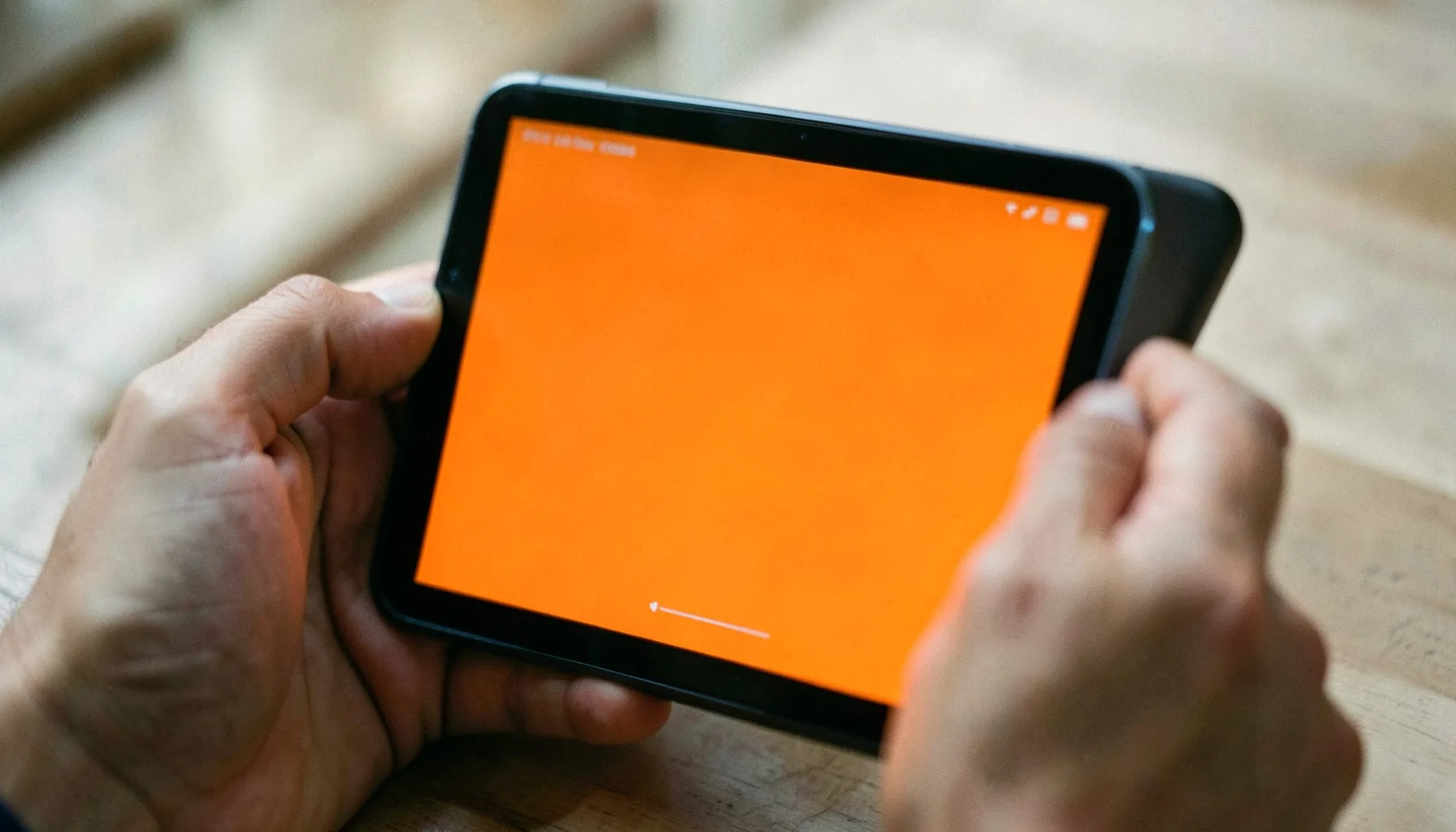 Bir tablet ekranında arayüz taslağı inceleyen ellerin yakın çekimi, nötr tonlu belgesel fotoğrafı